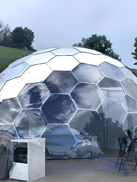 Bolla glamping specchiata su un prato collinare